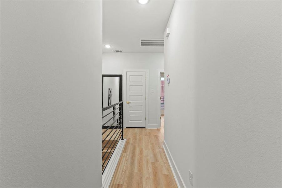 Hall with light wood-type flooring, baseboards, and visible vents