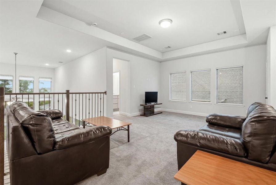 This bright and spacious upstairs living area features plush carpeting, modern recessed lighting, and ample natural light from multiple windows. It's perfect for a cozy family room or entertainment space, with leather couches and a TV setup. This bright and spacious upstairs living area features plush carpeting, modern recessed lighting, and ample natural light from multiple windows. It's perfect for a cozy family room or entertainment space, with leather couches and a TV setup.
