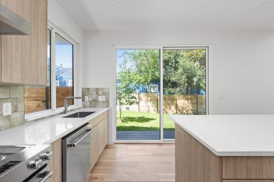 Kitchen with appliances with stainless steel finishes, a sink, modern cabinets, and light brown cabinets