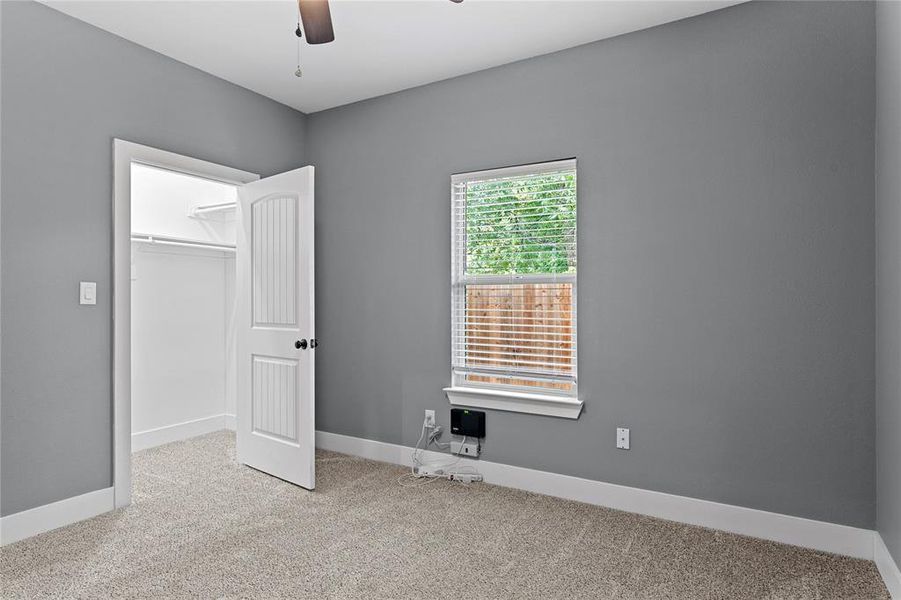Unfurnished bedroom featuring light colored carpet, a walk in closet, and ceiling fan Unfurnished bedroom featuring light colored carpet, a walk in closet, and ceiling fan