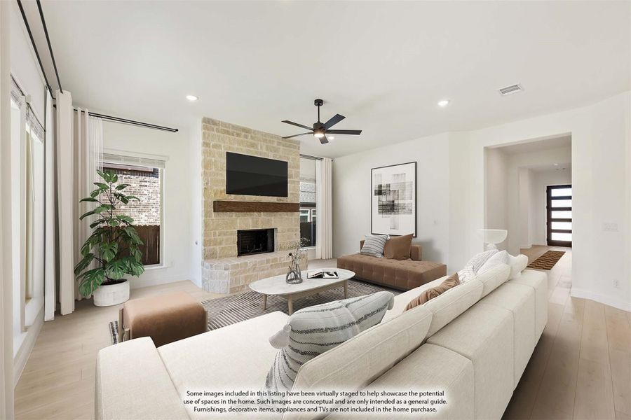Living room with stone fireplace, ceiling fan, white sectional sofa, and hardwood floors Living room with stone fireplace, ceiling fan, white sectional sofa, and hardwood floors