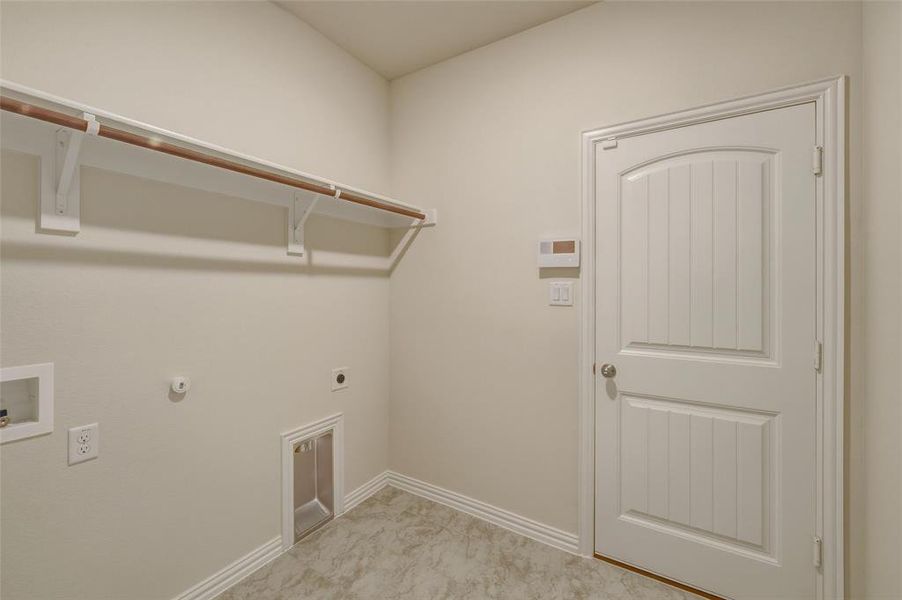 Utility room featuring a hanging rod, integrated dryer vent, washer hookup, and wood-panel door