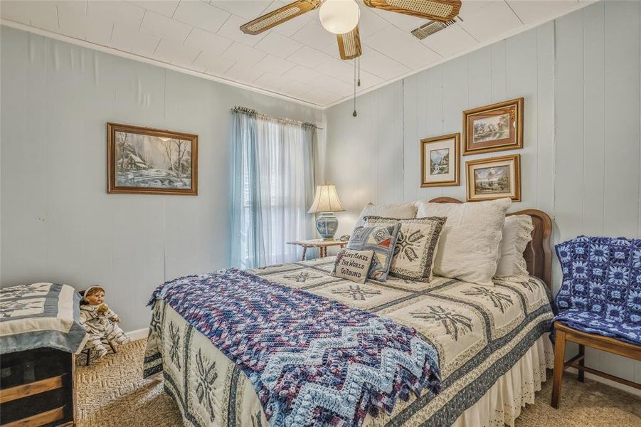 Room featuring light blue vertical paneling, a ceiling fan with woven blades, and a window with sheer drapes Room featuring light blue vertical paneling, a ceiling fan with woven blades, and a window with sheer drapes