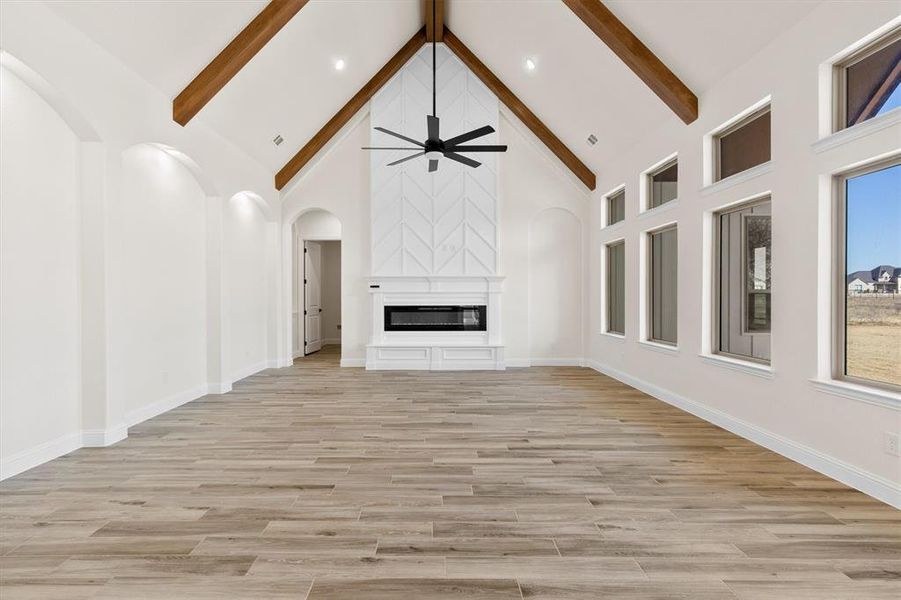 Lliving room featuring a large fireplace, high vaulted ceiling, beam ceiling, custom flooring