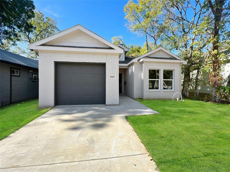 Ranch-style house featuring brick siding, a front yard, an attached garage, and concrete driveway
