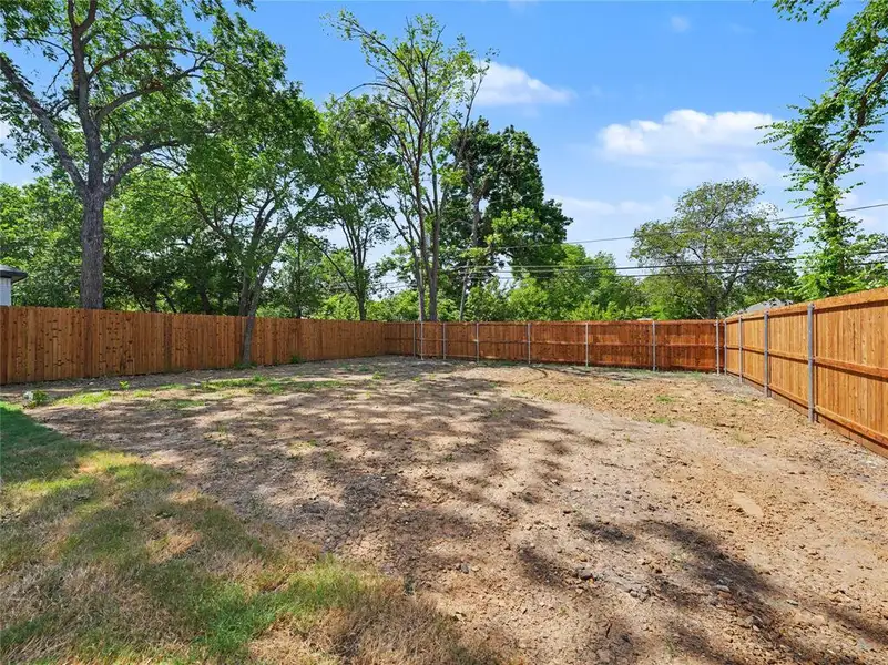 Spacious yard featuring a new wooden privacy fence and mature trees Spacious yard featuring a new wooden privacy fence and mature trees
