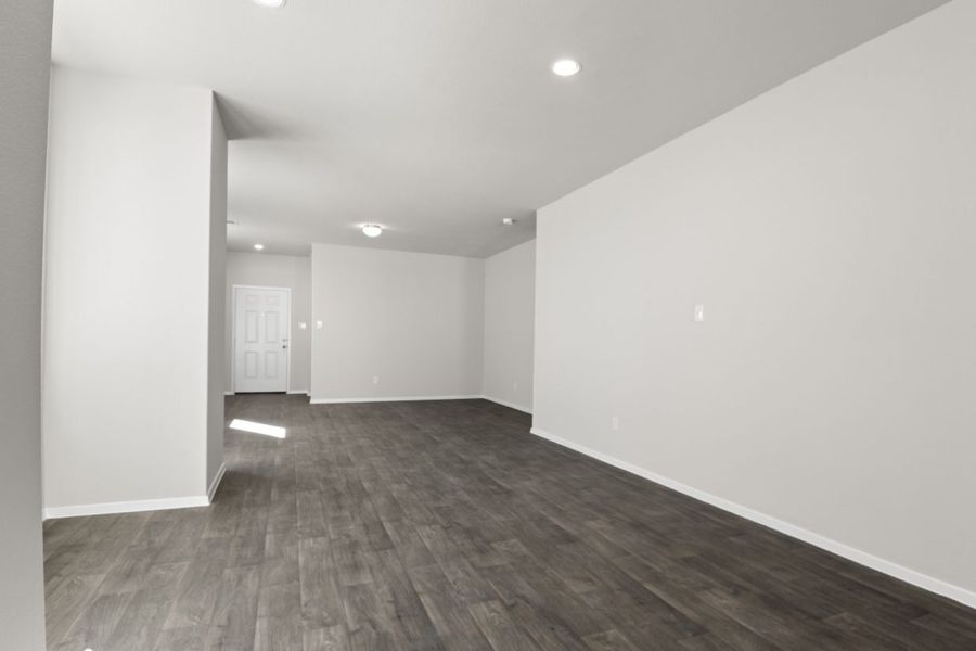 Image of a dining room area with light grey walls dark brown flooring, white trim and a white front door