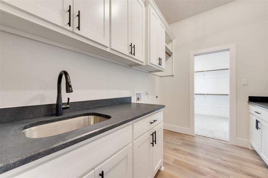 Kitchen featuring sink, white cabinets, and light hardwood / wood-style flooring