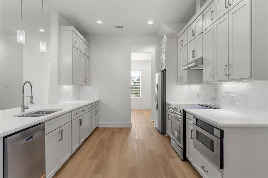 Kitchen featuring decorative backsplash, stainless steel appliances, hanging light fixtures, light stone counters, and recessed lighting Kitchen featuring decorative backsplash, stainless steel appliances, hanging light fixtures, light stone counters, and recessed lighting
