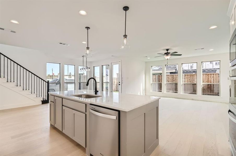 Kitchen featuring a center island with sink, dishwasher, a wealth of natural light, and light hardwood / wood-style flooring