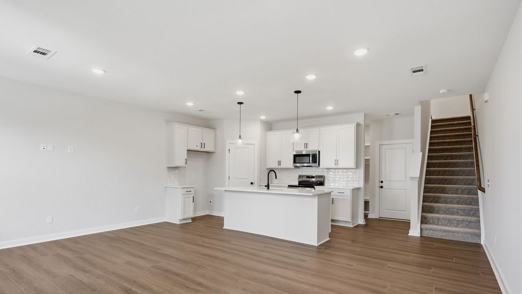Kitchen with island and pantry door next to entryway and stairs