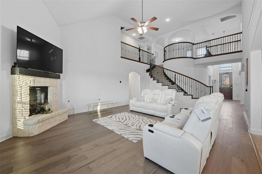Living area featuring high vaulted ceiling, wood finished floors, a fireplace, ceiling fan, and arched walkways Living area featuring high vaulted ceiling, wood finished floors, a fireplace, ceiling fan, and arched walkways