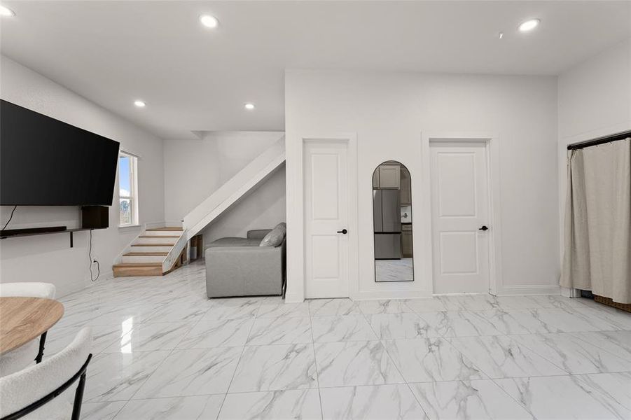 Living area featuring light marble finish floors, recessed lighting, and stairway