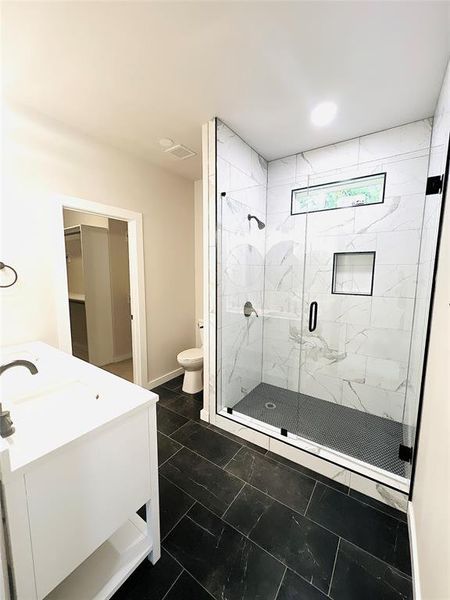 Bathroom featuring vanity, toilet, and a shower with door