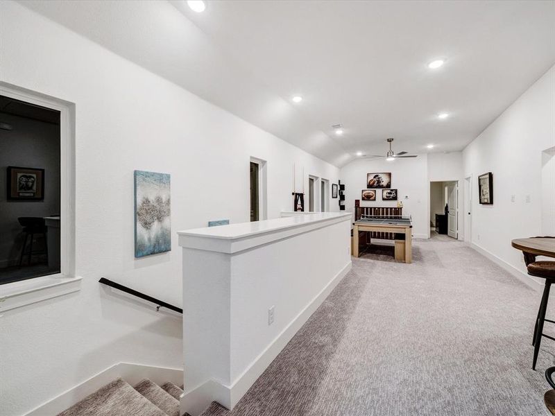 Hall with recessed lighting, light carpet, lofted ceiling, and an upstairs landing Hall with recessed lighting, light carpet, lofted ceiling, and an upstairs landing