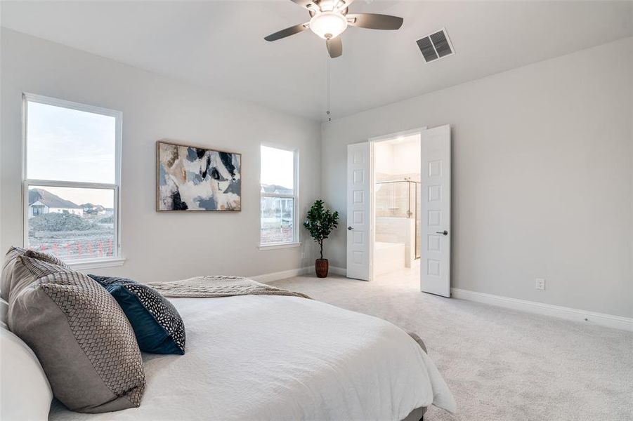 Carpeted bedroom with ceiling fan, lofted ceiling, and ensuite bath