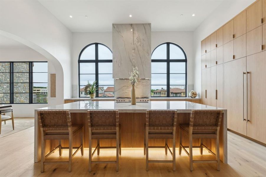 Kitchen with modern cabinets, light stone countertops, plenty of natural light, a spacious island, and recessed lighting Kitchen with modern cabinets, light stone countertops, plenty of natural light, a spacious island, and recessed lighting