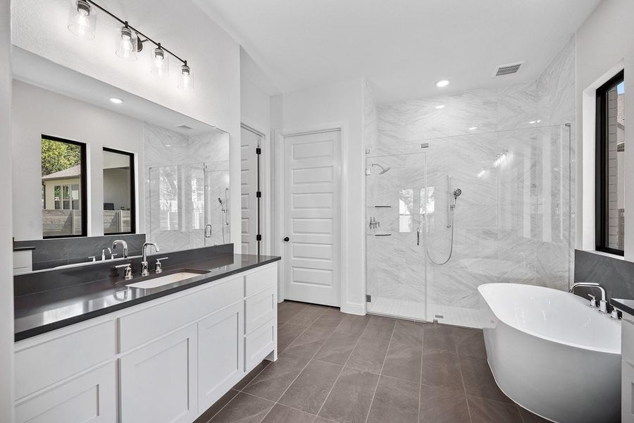 Full bathroom with a marble finish shower, a freestanding bath, vanity, and recessed lighting Full bathroom with a marble finish shower, a freestanding bath, vanity, and recessed lighting
