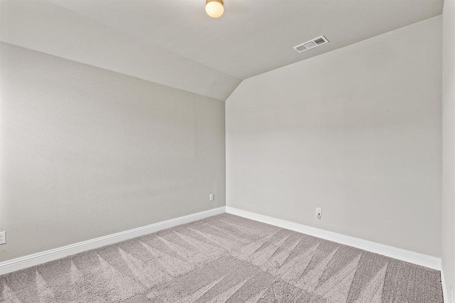 Carpeted empty room featuring vaulted ceiling