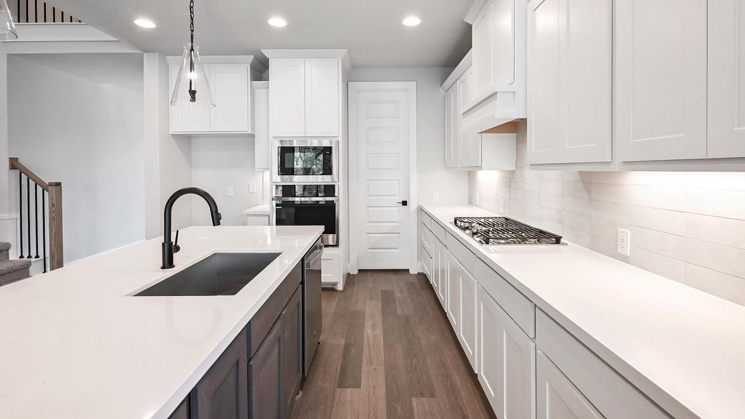 Kitchen with recessed lighting, light countertops, white cabinets, dark wood-type flooring, and stainless steel appliances