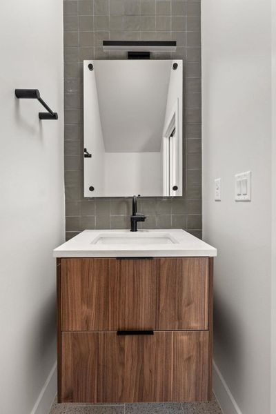 Bathroom with vanity, tasteful backsplash, baseboards, and speckled floor