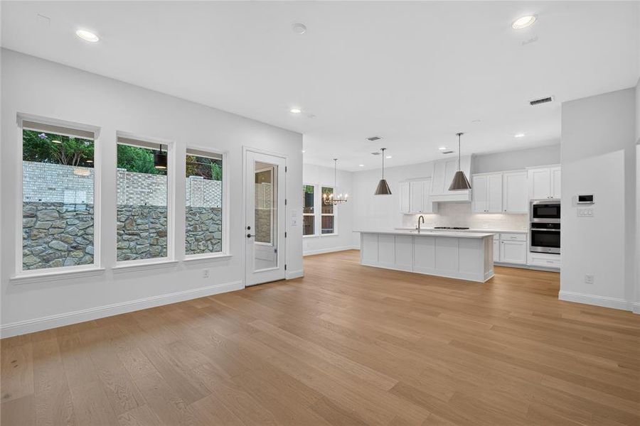 Open-concept room featuring wood-finish flooring, recessed lighting, and a modern kitchen Open-concept room featuring wood-finish flooring, recessed lighting, and a modern kitchen