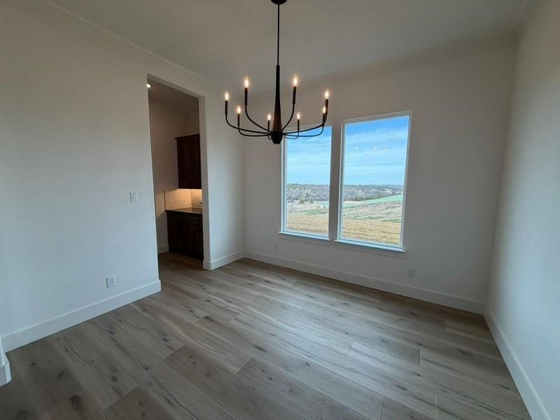 Unfurnished dining area featuring light wood-type flooring, crown molding, and a chandelier