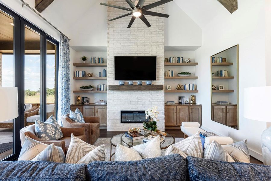 Living room with a ceiling fan, built in shelves, a brick fireplace, and wood finished floors Living room with a ceiling fan, built in shelves, a brick fireplace, and wood finished floors