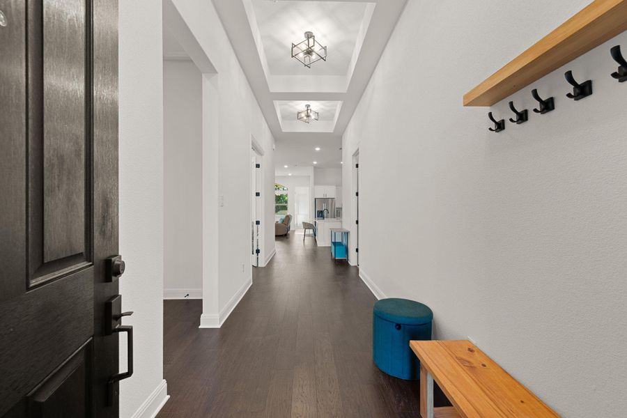 A well-lit entry hall with dark hard surfaced floors leads to an open-concept living space. A well-lit entry hall with dark hard surfaced floors leads to an open-concept living space.