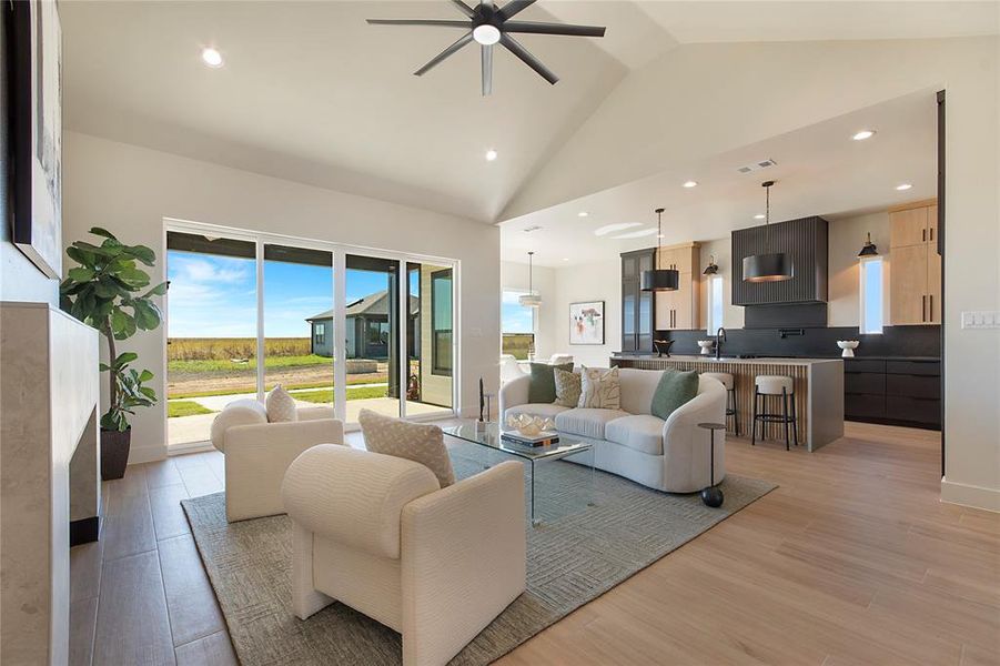 Living area with recessed lighting, light wood-style flooring, high vaulted ceiling, and ceiling fan Living area with recessed lighting, light wood-style flooring, high vaulted ceiling, and ceiling fan