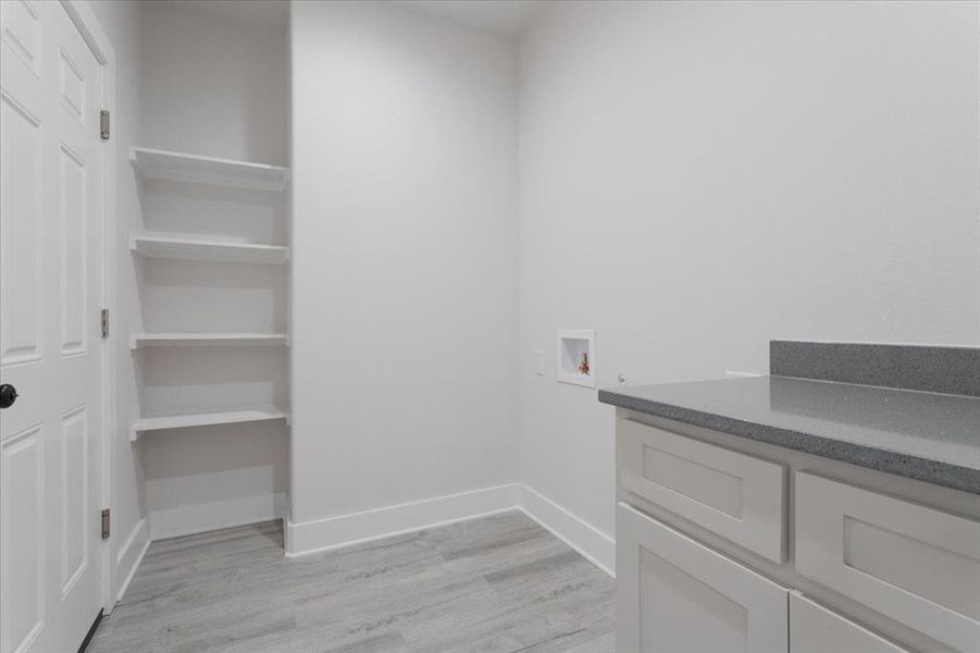 Laundry area featuring cabinets, light wood-type flooring, and washer hookup