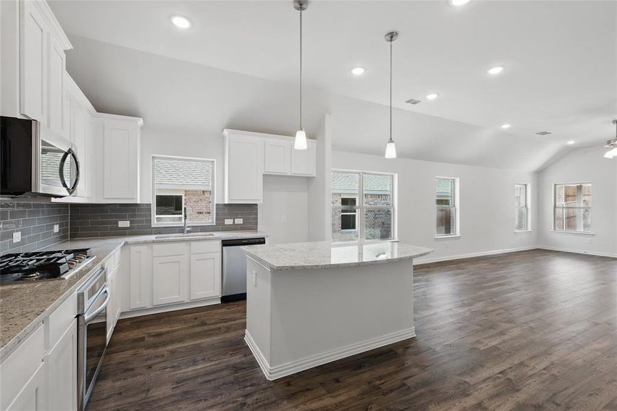 Kitchen with stainless steel appliances, a ceiling fan, white cabinetry, vaulted ceiling, and a sink