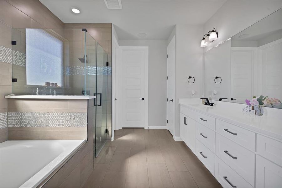 Bathroom with a stall shower, visible vents, a garden tub, and vanity