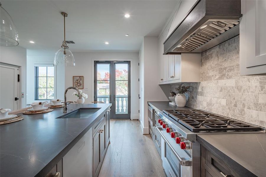 Kitchen with premium range hood, stainless steel range, sink, light hardwood / wood-style flooring, and white cabinets