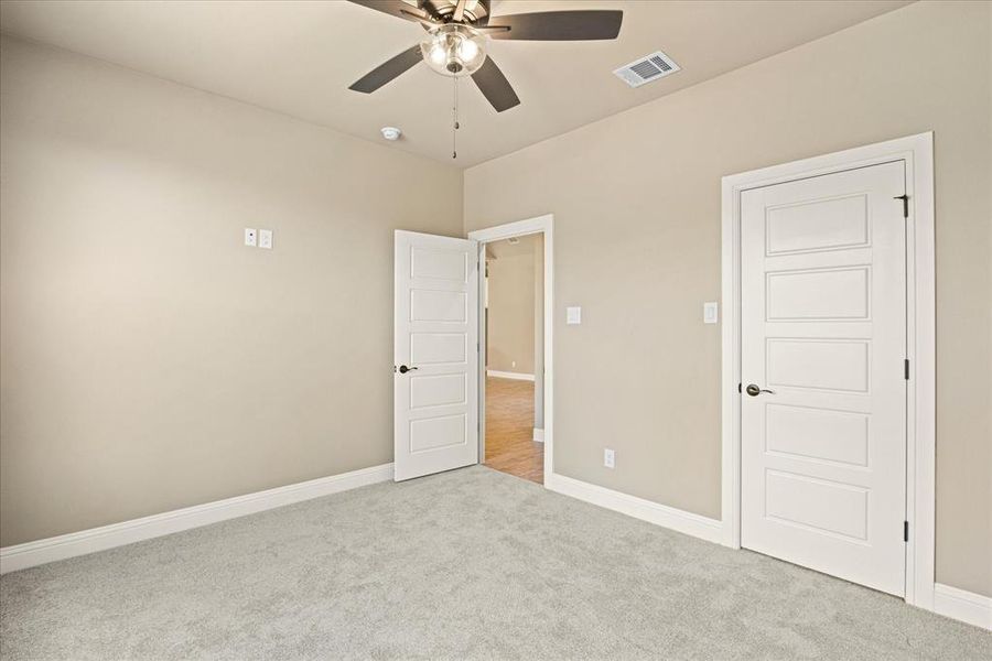 Unfurnished bedroom with ceiling fan and light colored carpet