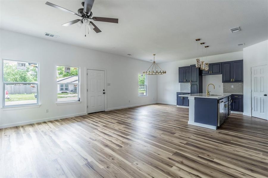Kitchen with open floor plan, a chandelier, light countertops, a sink, and wood finished floors Kitchen with open floor plan, a chandelier, light countertops, a sink, and wood finished floors