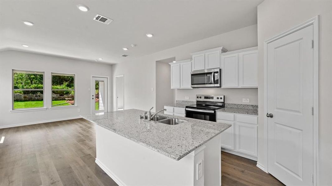 Modern kitchen featuring a central island with an undermount dual-basin sink and a speckled countertop