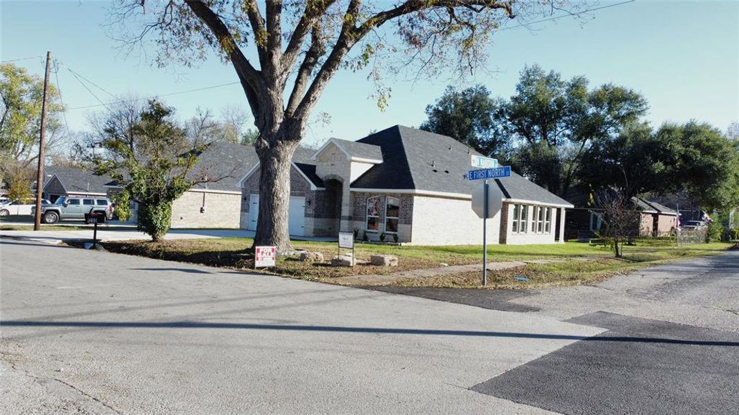 View of front of home with a residential view, brick siding, a front yard, and driveway