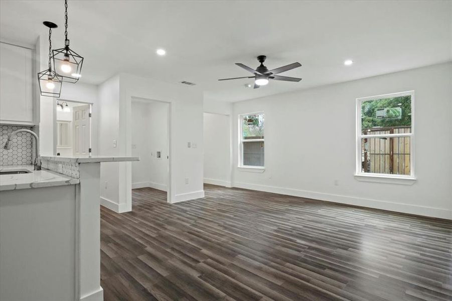 Unfurnished living room with dark hardwood / wood-style flooring, a wealth of natural light, sink, and ceiling fan