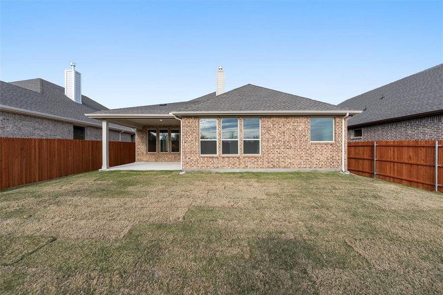 Back of house featuring a patio, a fenced backyard, brick siding, and a shingled roof