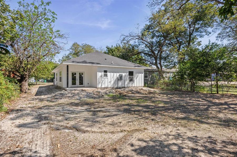 Back of property featuring french doors, a shingled roof, and a patio
