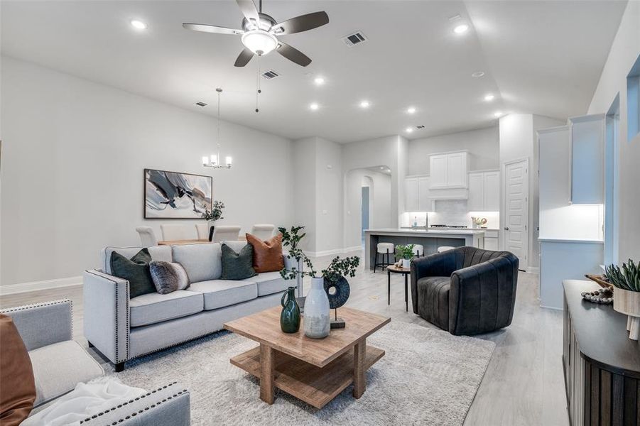 Living room featuring ceiling fan with notable chandelier and light hardwood / wood-style floors