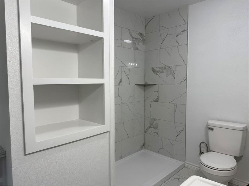 Bathroom featuring a shower stall and toilet