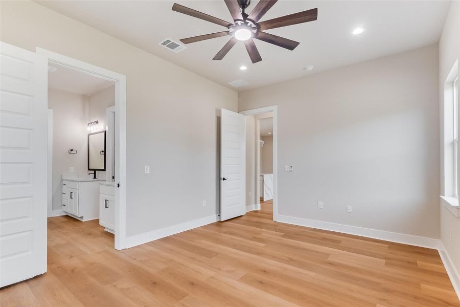 Unfurnished bedroom with light wood-style floors, recessed lighting, and ensuite bath Unfurnished bedroom with light wood-style floors, recessed lighting, and ensuite bath