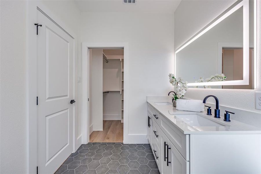 Bathroom featuring double vanity, tile patterned floors, and a walk in closet Bathroom featuring double vanity, tile patterned floors, and a walk in closet