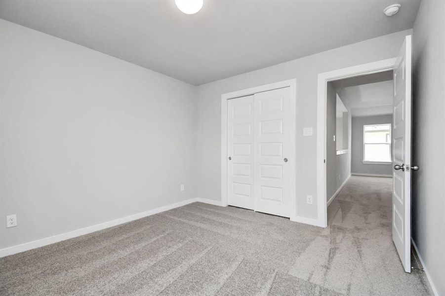 Generously sized secondary bedrooms featuring spacious closets, soft and inviting carpeting underfoot, large windows allowing plenty of natural light. Sample photo of completed home. Actual colors and selections may vary.