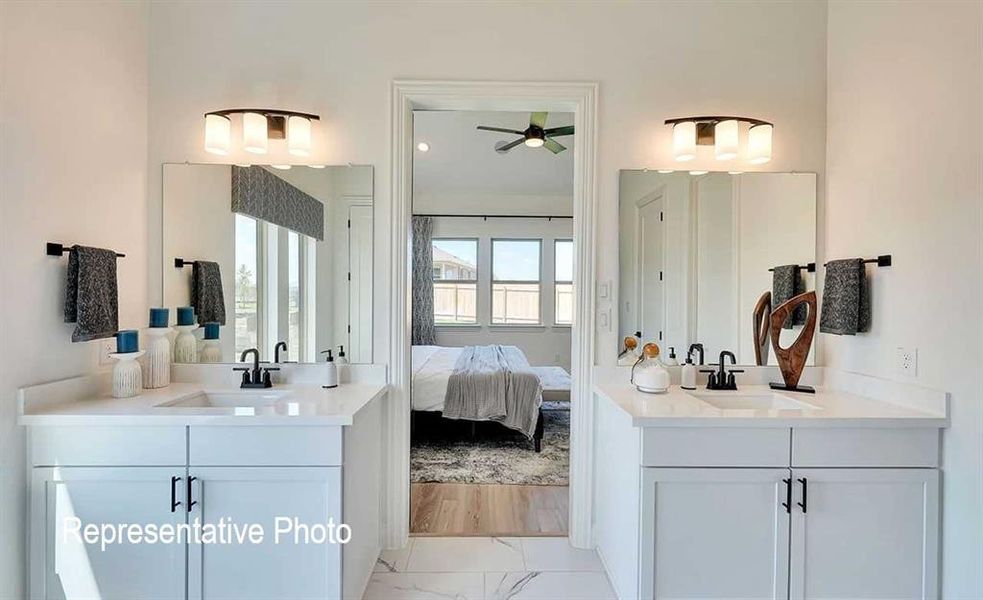 Dual vanity bathroom featuring white cabinetry, solid surface countertops, and rectangular under-mount sinks