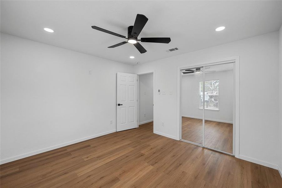 Bedroom featuring wood-finish flooring, white walls, recessed lighting, and a contemporary ceiling fan Bedroom featuring wood-finish flooring, white walls, recessed lighting, and a contemporary ceiling fan