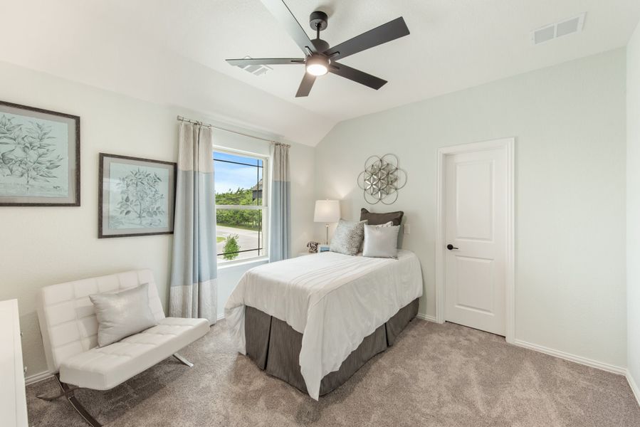 Bedroom with vaulted ceiling, ceiling fan, carpet floors, and a window with light blue curtains Bedroom with vaulted ceiling, ceiling fan, carpet floors, and a window with light blue curtains