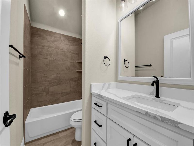 Full bathroom featuring tiled shower / bath, vanity, wood-type flooring, and toilet